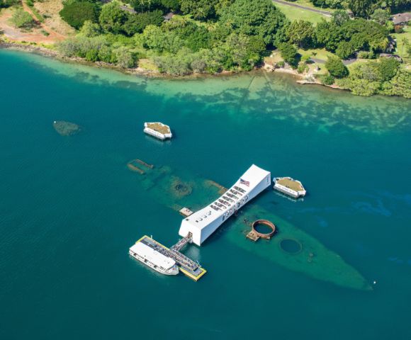 The USS Arizona is anchored in the ocean, surrounded by calm waters and a clear blue sky.