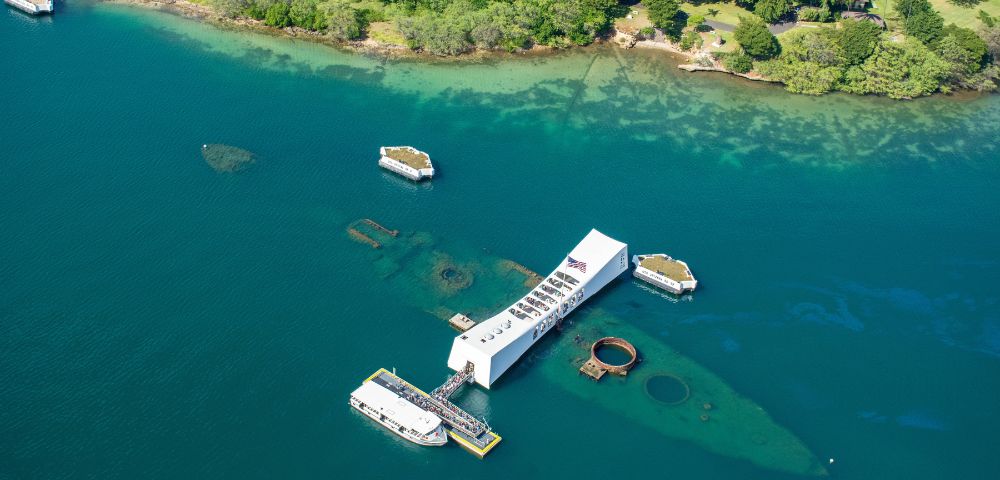 The USS Arizona is anchored in the ocean, surrounded by calm waters and a clear blue sky.