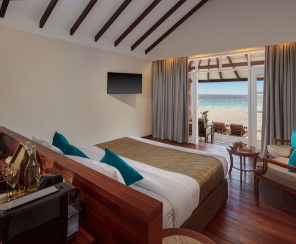 Large windows with sheer curtains provide an unobstructed view of the sandy beach and ocean.