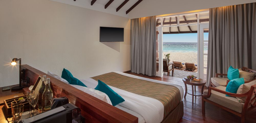 Large windows with sheer curtains provide an unobstructed view of the sandy beach and ocean.