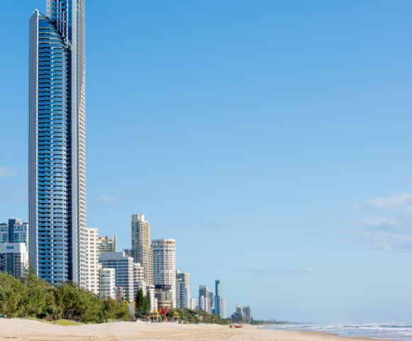 Tall skyscrapers line the beach under a clear blue sky, showcasing the vibrant skyline of a coastal city.