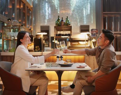 A couple toasting with glasses in an elegant restaurant setting.