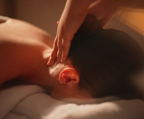 Relaxing massage scene featuring a person receiving a neck massage, with soft lighting and a serene ambiance.