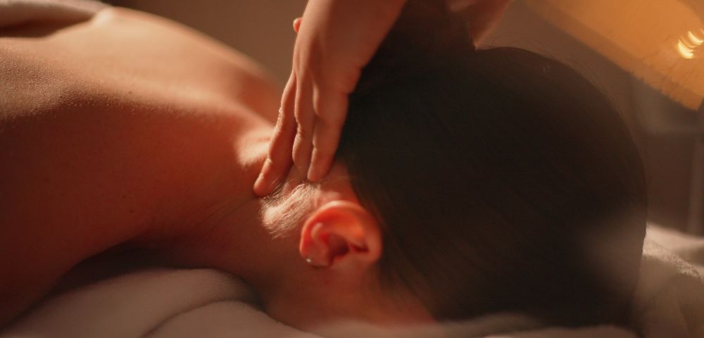 Relaxing massage scene featuring a person receiving a neck massage, with soft lighting and a serene ambiance.