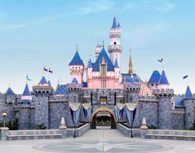 A pastel-colored fairy tale castle with blue turrets and pink walls, under a clear sky. Flags wave gently, evoking a magical, whimsical atmosphere.