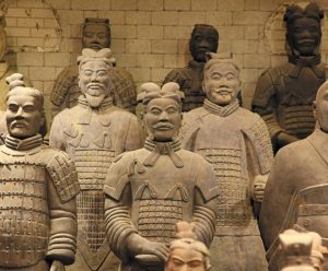 Terracotta soldiers with detailed armor and unique facial expressions, standing in rows. The earthy tones convey a sense of ancient, historical significance.