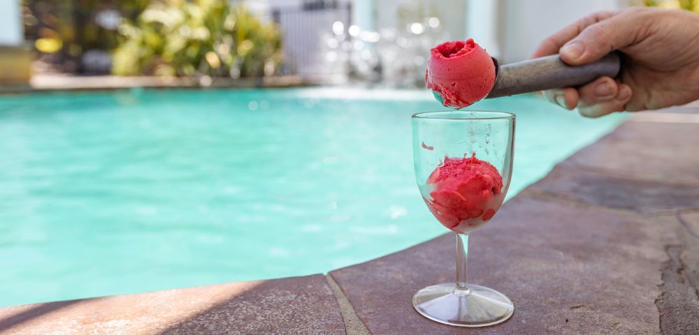 A luxurious frozen sorbet dessert displayed in a wine glass, beside the poolside.
