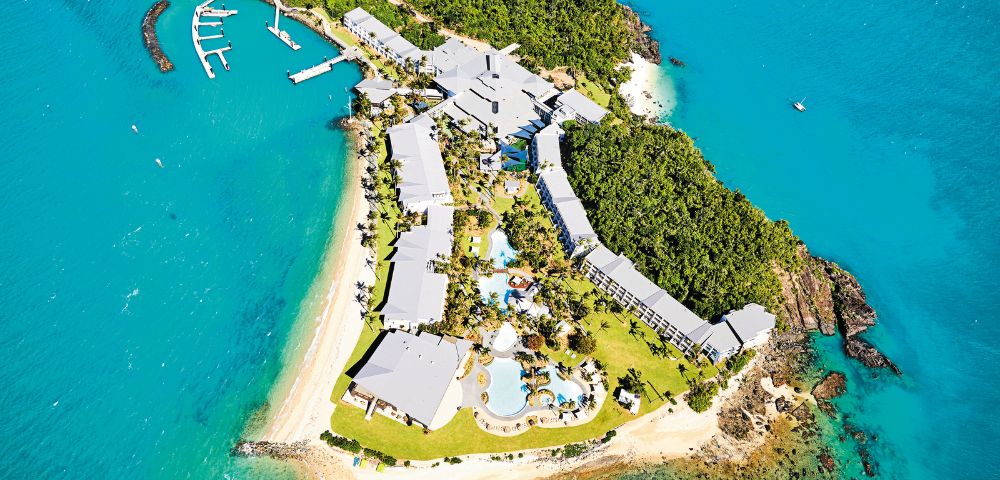 Aerial view of a tropical resort on a picturesque island, surrounded by turquoise waters and lush greenery. Relaxation and luxury await.
