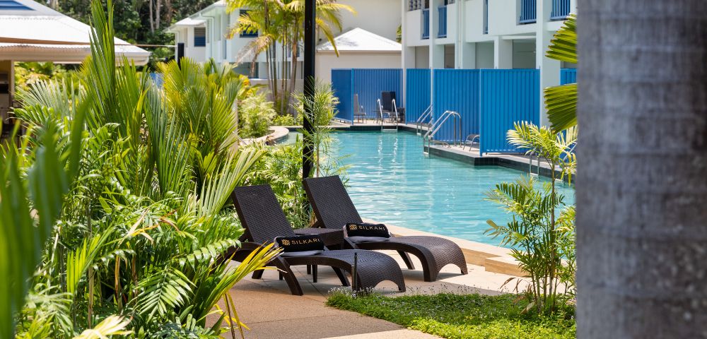 A resort pool area featuring lounge chairs and umbrellas, inviting relaxation under the sun.
