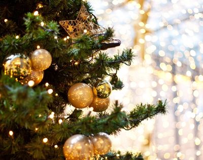 Christmas tree adorned with gold baubles, a star ornament, and twinkling lights. The background glows softly, creating a warm, festive ambiance.