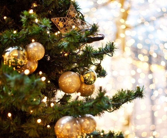 Christmas tree adorned with gold baubles, a star ornament, and twinkling lights. The background glows softly, creating a warm, festive ambiance.