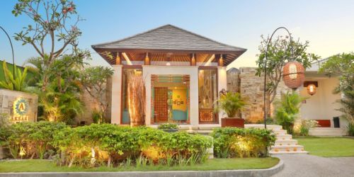 A charming modern villa with a sloped roof, surrounded by lush greenery and warm lighting, inviting entrance.