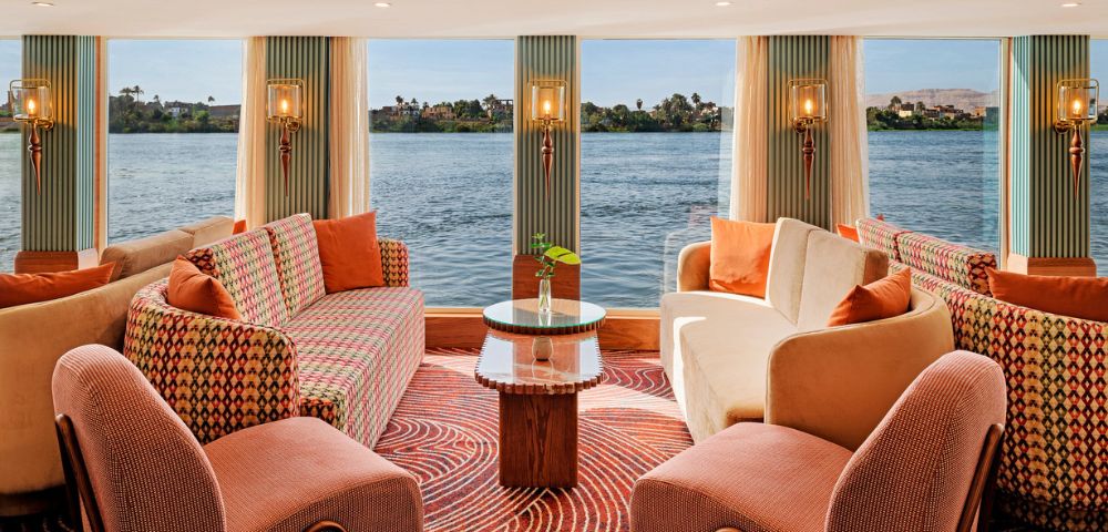Cozy boat living room with large windows showcasing a serene view of the water outside.