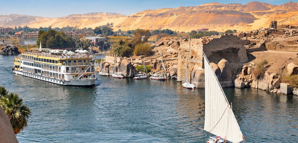 The Nile River flowing through Egypt, surrounded by lush greenery and ancient structures along its banks.