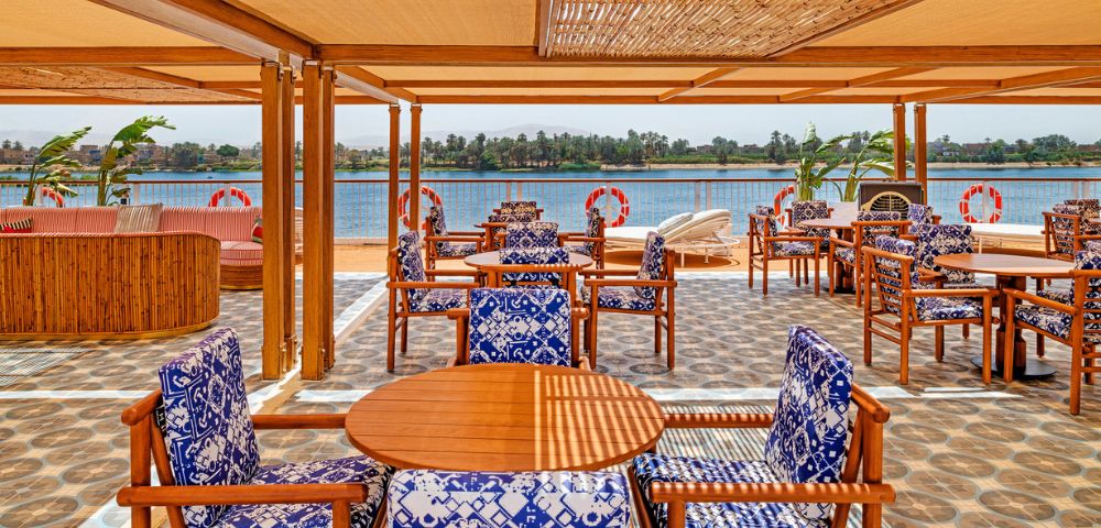 A restaurant featuring wooden tables and chairs with a scenic view of the water.