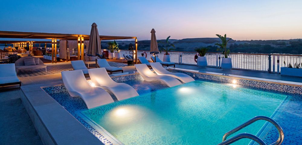 Sunset over a pool surrounded by lounge chairs and umbrellas, creating a serene and inviting atmosphere.