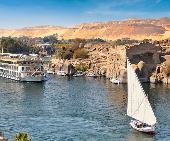 The Nile River flowing through Egypt, surrounded by lush greenery and ancient structures along its banks.