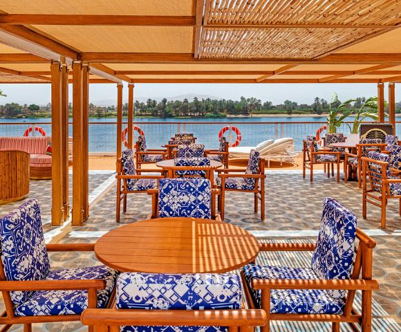 A restaurant featuring wooden tables and chairs with a scenic view of the water.