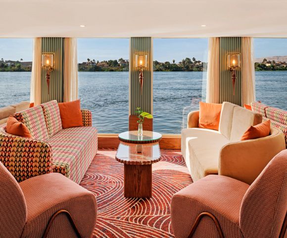 Cozy boat living room with large windows showcasing a serene view of the water outside.