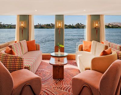 Cozy boat living room with large windows showcasing a serene view of the water outside.