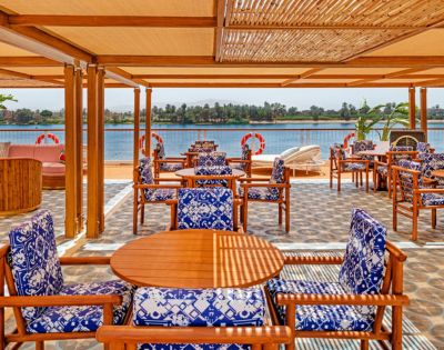 A restaurant featuring wooden tables and chairs with a scenic view of the water.