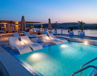 Sunset over a pool surrounded by lounge chairs and umbrellas, creating a serene and inviting atmosphere.