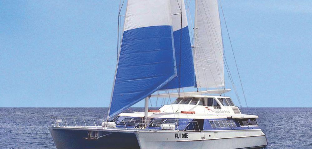 A catamaran with colorful blue, red, and white sails branded 