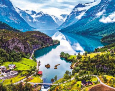 A scenic fjord landscape with a reflective lake, surrounded by snow-capped mountains and lush green forests. Small houses dot the picturesque valley.