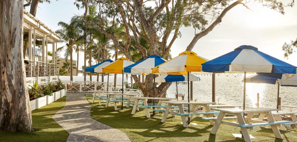 Beach umbrellas under the sun's soft lighting and serene lush greeneries.