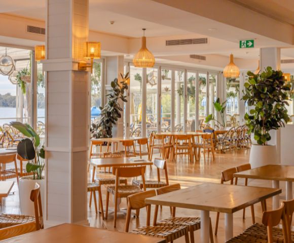 Restaurant's dining exterior featuring chandeliers and dim yellow lights and display plants.