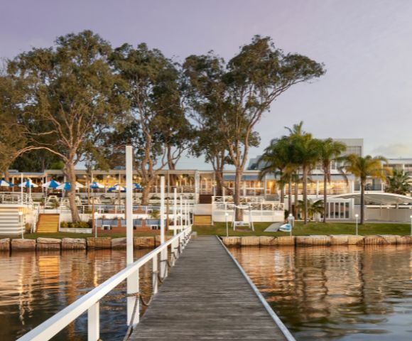 The image depicts wooden pathway in the middle of the lake through the resort's restaurant.