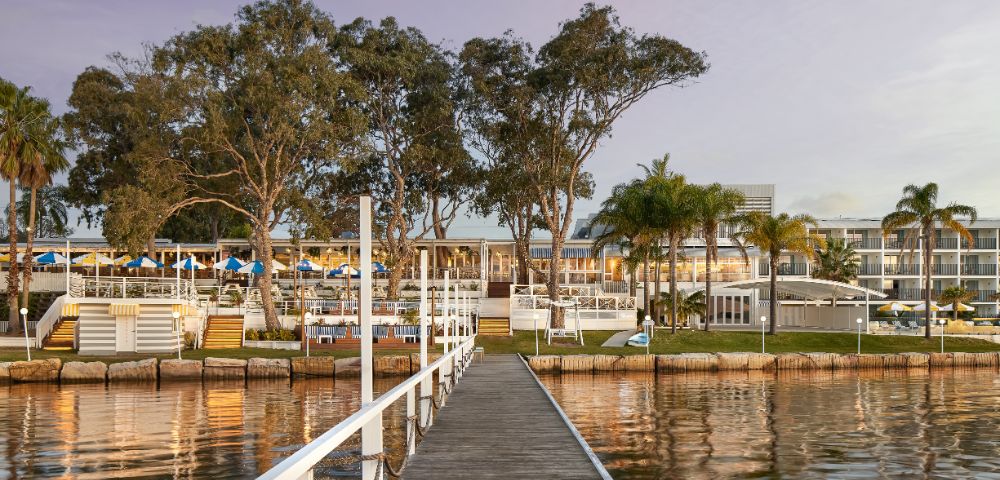 The image depicts wooden pathway in the middle of the lake through the resort's restaurant.
