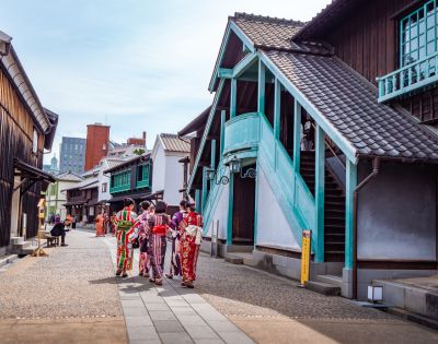 A group of people in traditional Japanese kimonos walking along a street lined with old-style wooden buildings.