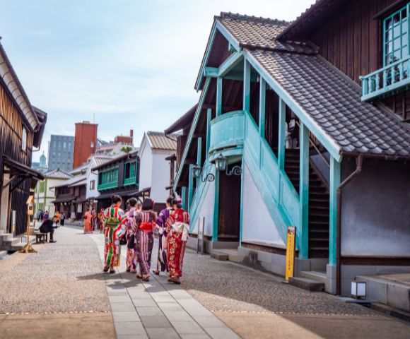 A group of people in traditional Japanese kimonos walking along a street lined with old-style wooden buildings.