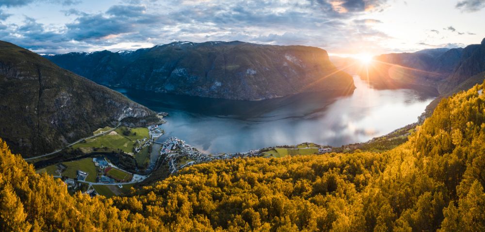 Breathtaking fjord surrounded by mountains at sunset, bathed in golden light.