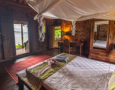 The image features a cozy bedroom with a large bed occupying the majority of the space. The bed is positioned near a window, allowing natural light to enter the room. The room also has a chair and a dining table, creating a comfortable living area. In addition to the main furniture, there are several bottles scattered around the room, possibly indicating that the occupants enjoy various beverages. A vase can also be seen, adding a touch of decoration to the space. The overall atmosphere of the room is inviting and comfortable, making it an ideal place to relax and unwind --ar 580:480 --q 2 --s 750 --v 5.2