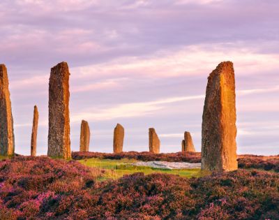Ring of Brodgar, Scotland – A Neolithic stone circle with tall standing stones silhouetted against a vivid sunset sky on the Orkney Islands.
