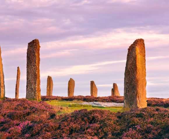 Ring of Brodgar, Scotland – A Neolithic stone circle with tall standing stones silhouetted against a vivid sunset sky on the Orkney Islands.