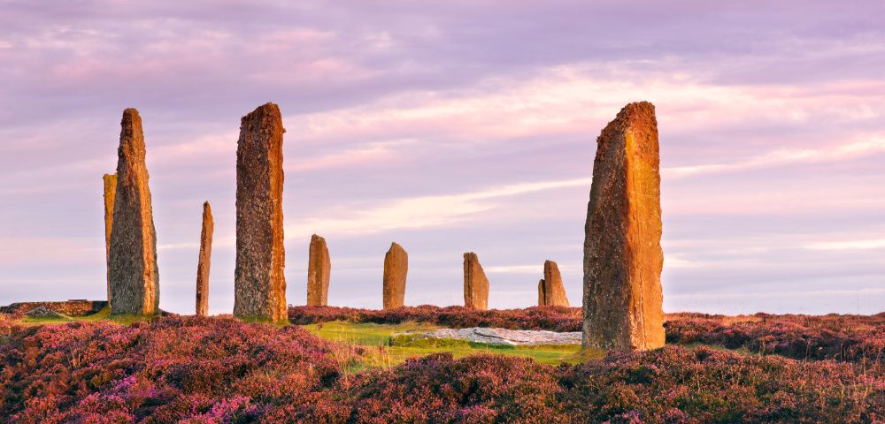 Ring of Brodgar, Scotland – A Neolithic stone circle with tall standing stones silhouetted against a vivid sunset sky on the Orkney Islands.