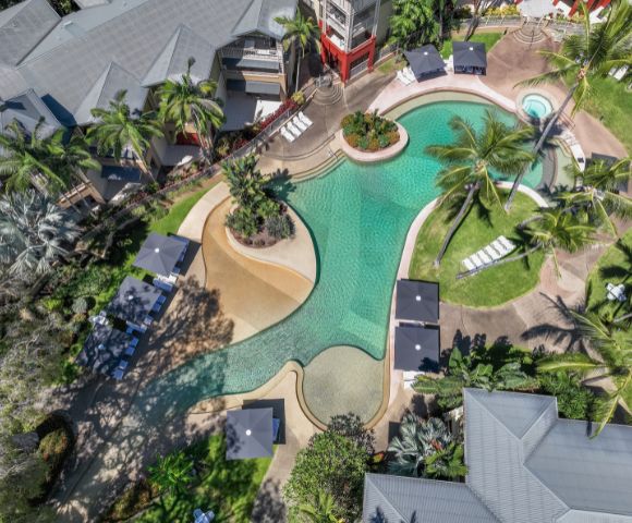Aerial view of the resort’s pool area surrounded by tropical plants and winding pathways.
