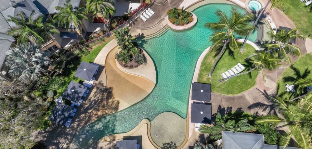 Aerial view of the resort’s pool area surrounded by tropical plants and winding pathways.