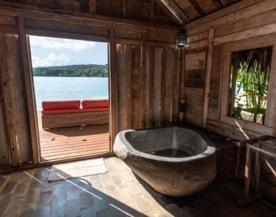 Bathroom with a freestanding tub offering an ocean view through an open door.