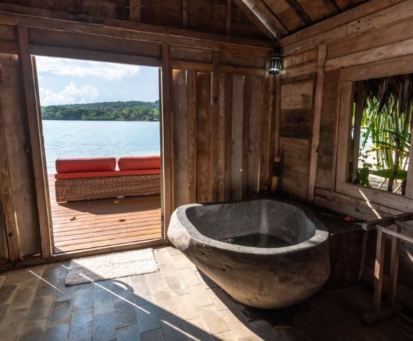 Bathroom with a freestanding tub offering an ocean view through an open door.