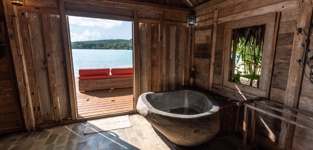 Bathroom with a freestanding tub offering an ocean view through an open door.