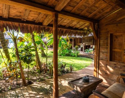 Outdoor seating area under a wooden roof with views of lush tropical greenery.