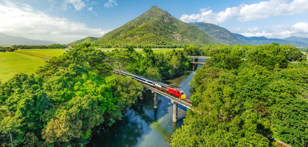 Lush green landscape with a river winding through it and a zip line crossing overhead.