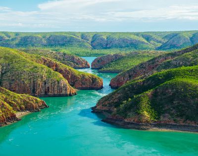 Aerial view of winding rivers flowing through green hills and valleys.