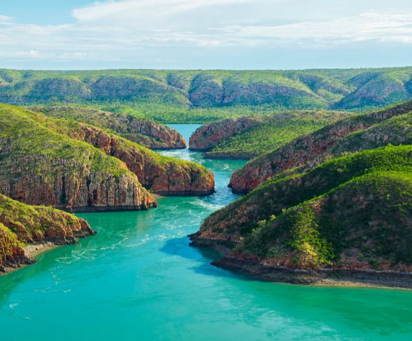 Aerial view of winding rivers flowing through green hills and valleys.