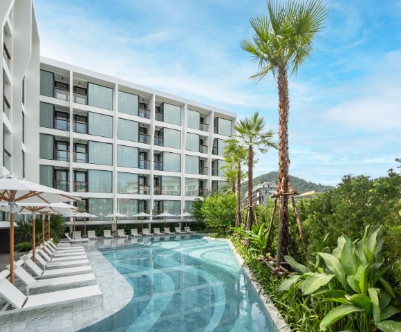 A luxurious hotel pool area with palm trees, lounge chairs, and a modern building in the background.