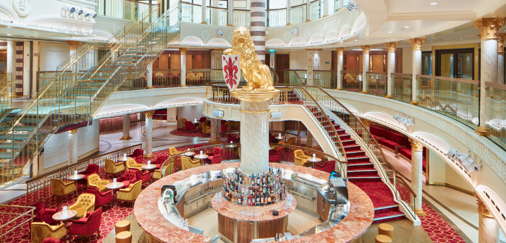 Elegant main area onboard cruise ship with open bar and staircase.